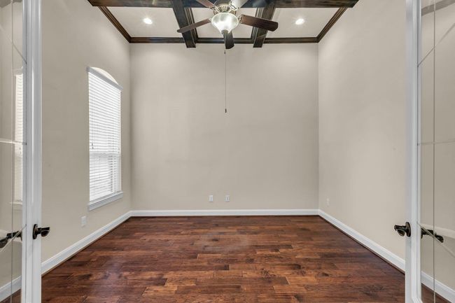 This elegant home office features double doors that provide privacy while the rich wood coffered ceiling adds architectural interest and warmth. The spacious layout and ample natural light create an inspiring environment for productivity and focus. | Image 18