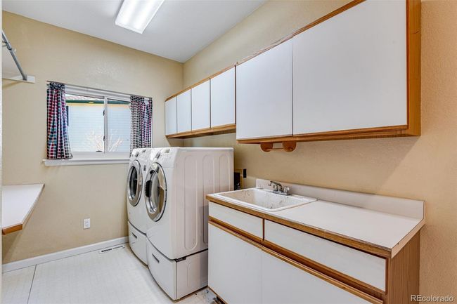 Laundry room with cabinet space, washing machine and clothes dryer, baseboards, and a sink | Image 15