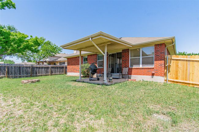 Rear view of property featuring a yard, a fenced backyard, a patio area, and brick siding | Image 18