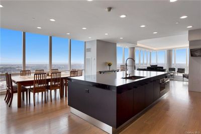 Kitchen featuring a kitchen island with sink, a water view, light hardwood / wood-style flooring, sink, and expansive windows | Image 3