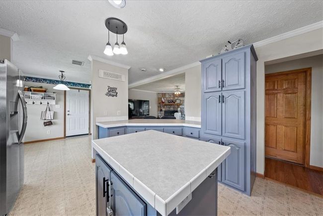 Kitchen featuring light countertops, stainless steel fridge, a center island, and light floors | Image 12