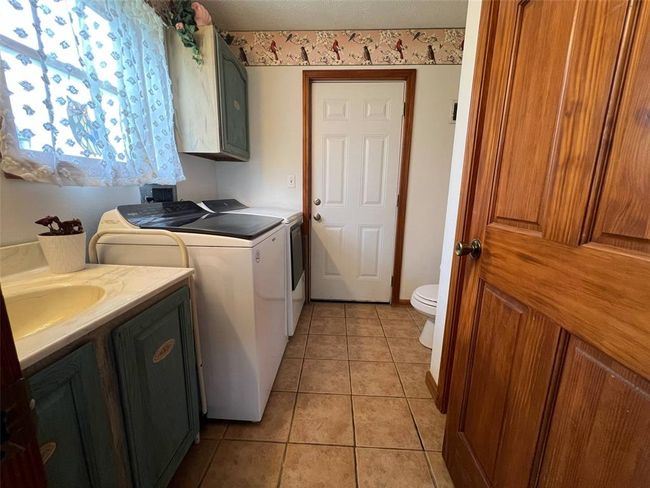 Laundry room with independent washer and dryer and light tile patterned floors | Image 10