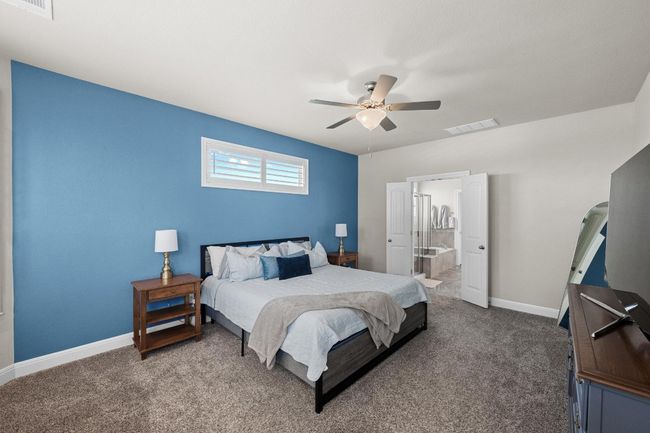 Carpeted Primary bedroom featuring ceiling fan and ensuite bath with tub and shower stall, 2 sinks and walk -in closet. | Image 20