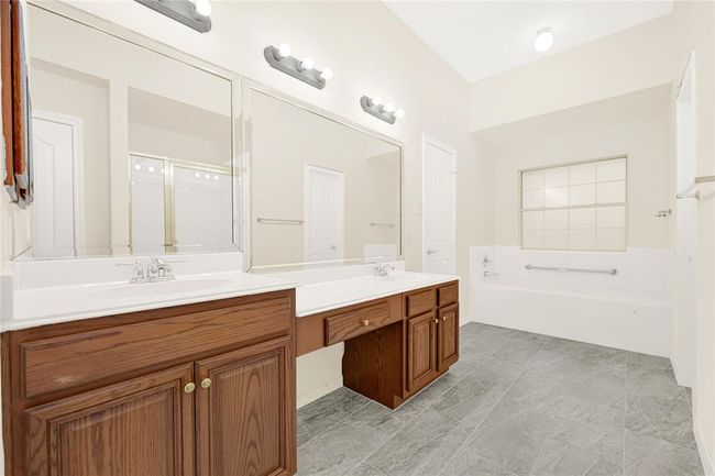 This primary bathroom features a jetted tub, perfect for relaxation. Completing the space is a vanity with dual sinks, offering ample counter space, and a separate shower for convenience. | Image 17