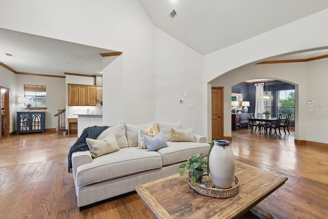 Living room with arched walkways, plenty of natural light, wood finished floors, a high ceiling, and crown molding | Image 10