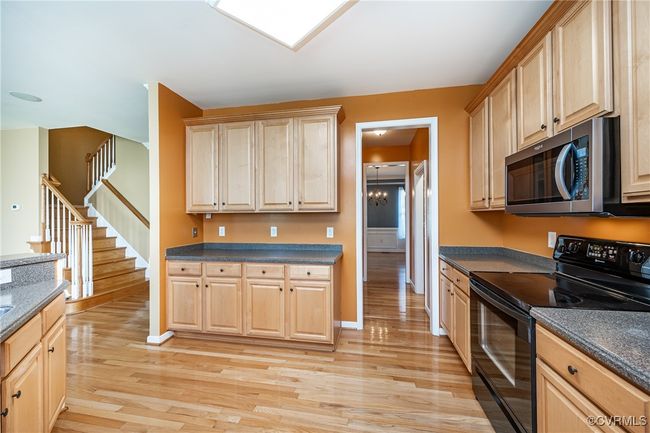 Kitchen featuring black / electric stove, stainless steel microwave, and light brown cabinets | Image 13