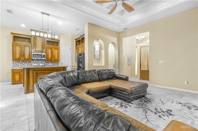 Living room featuring light tile patterned flooring and ceiling fan with notable chandelier | Image 12