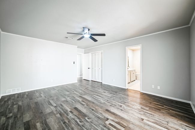 Unfurnished bedroom with dark wood-style floors, visible vents, baseboards, and ornamental molding | Image 10
