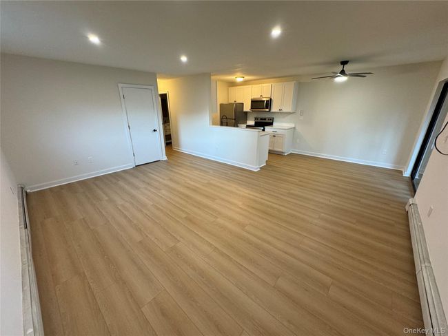 Unfurnished living room with light wood finished floors, ceiling fan, recessed lighting, and a baseboard heating unit | Image 15