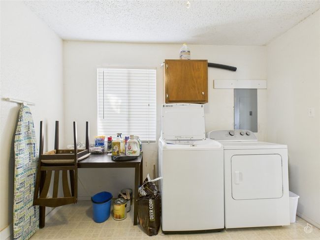 Laundry room with electric panel, cabinet space, a textured ceiling, and separate washer and dryer. | Image 24