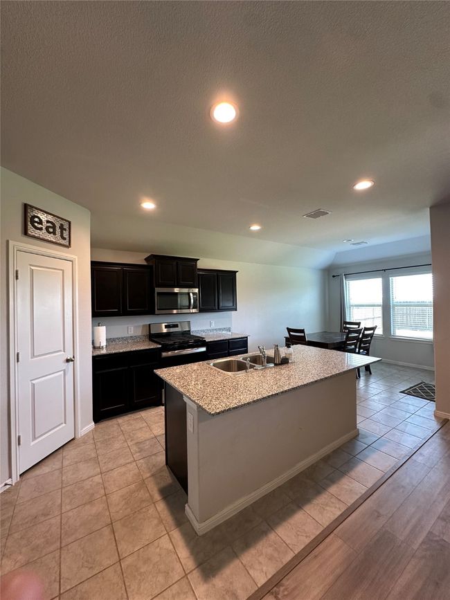 Kitchen with a sink, a center island with sink, appliances with stainless steel finishes, dark cabinets, and visible vents | Image 18