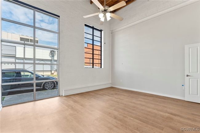 Unfurnished room with a ceiling fan, baseboards, wood finished floors, and a towering ceiling | Image 16
