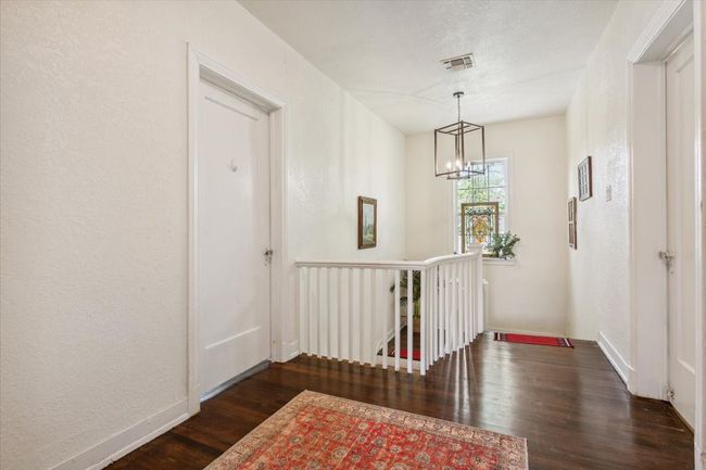 Hall with visible vents, baseboards, an inviting chandelier, an upstairs landing, and dark wood finished floors | Image 17