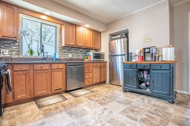 kitchen featuring crown molding, a sink, brown cabinetry, stainless steel appliances, and backsplash | Image 8