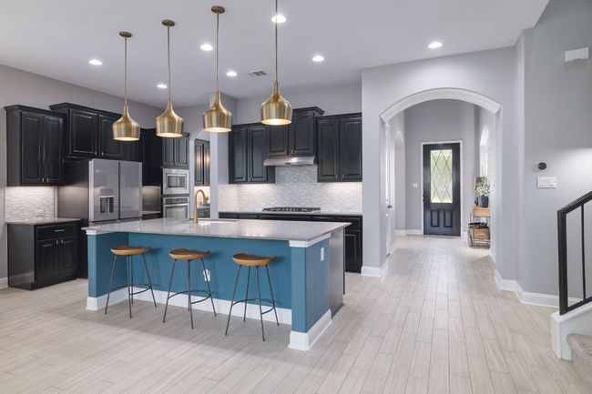 Kitchen with arched walkways, stainless steel appliances, under cabinet range hood, a sink, and backsplash | Image 6