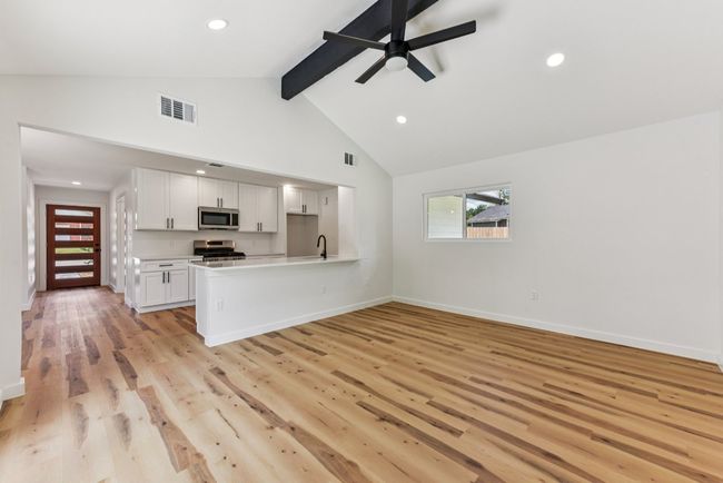 Unfurnished living room featuring beamed ceiling, light wood-style flooring, recessed lighting, high vaulted ceiling, and ceiling fan | Image 7