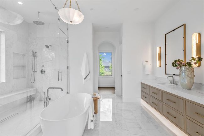 This luxurious primary bathroom features a double canity with custom cabinetry that combines both style and functionality underlighting. The spacious walk-in shower and elegant standalone bathtub create a spa-like atmosphere. | Image 39