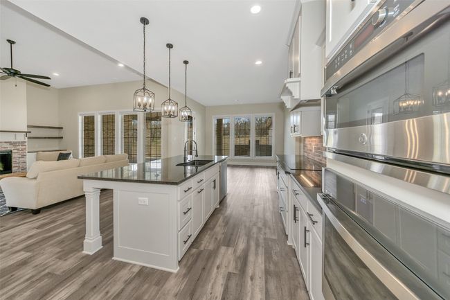Kitchen featuring a kitchen bar, wood finished floors, white cabinetry, and a sink | Image 7