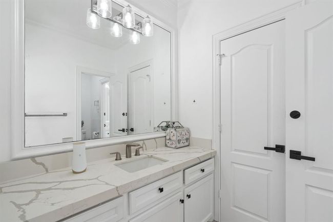 Well-appointed Jack and Jill bathroom with quartz countertops, an oversized mirror, and white cabinetry. A bright, airy space with ample storage that combines style and practicality. | Image 38