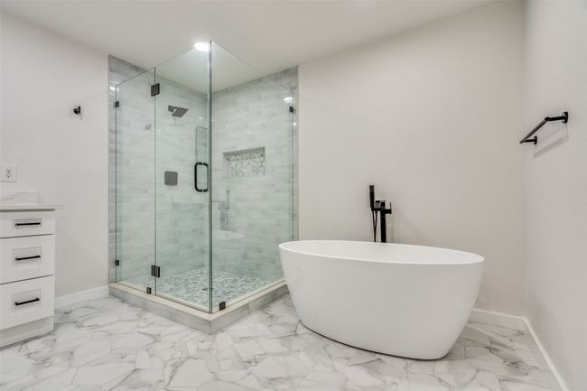 Full bath featuring a freestanding bath, a shower stall, marble look tiles, and vanity | Image 19