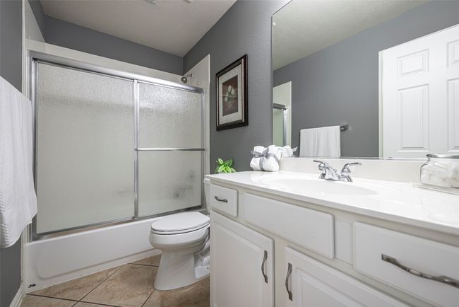 Bathroom featuring vanity, toilet, shower / tub combination with glass door, and tile patterned flooring | Image 23