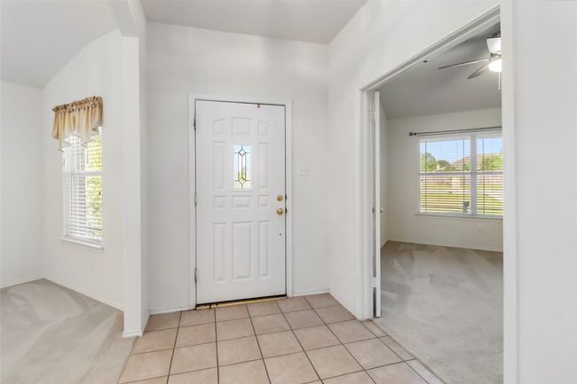 Entryway with light carpet, healthy amount of natural light, a ceiling fan, baseboards, and vaulted ceiling | Image 6