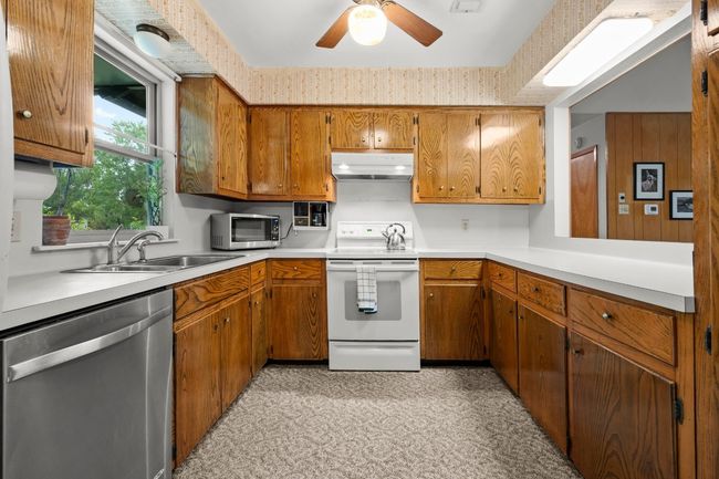 Kitchen with stainless steel appliances, under cabinet range hood, brown cabinetry, and ceiling fan | Image 11