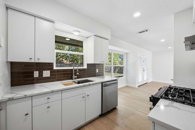 Kitchen featuring stainless steel dishwasher, decorative backsplash, light wood-style flooring, white cabinets, and recessed lighting | Image 15