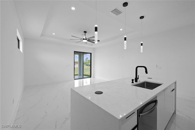 Kitchen featuring a sink, modern cabinets, light marble finish floors, a tray ceiling, and open floor plan | Image 11