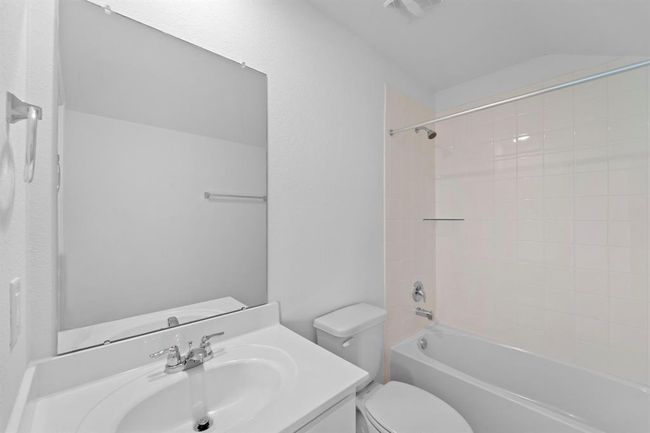 The secondary bath features tile flooring, white cabinetry and light countertops and a shower/tub combo. Perfect for accommodating any visiting family and friends. | Image 17