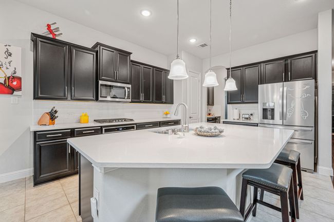 Kitchen featuring decorative backsplash, quartz countertops, stainless steel appliances, and a large island | Image 11