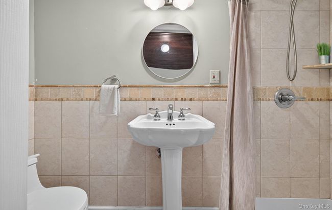Bathroom featuring a shower stall, tile walls, and a wainscoted wall | Image 14