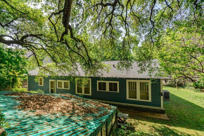 Rear view of house from rear of stone staircase path with heritage oak canopy overlooking greenhouse and lush yard. Home has recent shingles and features lush landscaping, and recent HVAC & water heater. | Image 5