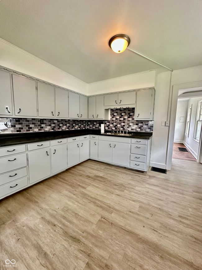 kitchen featuring visible vents, a sink, dark countertops, light wood-style floors, and decorative backsplash | Image 29