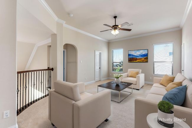Living room with light carpet, a ceiling fan, ornamental molding, baseboards, and arched walkways | Image 30