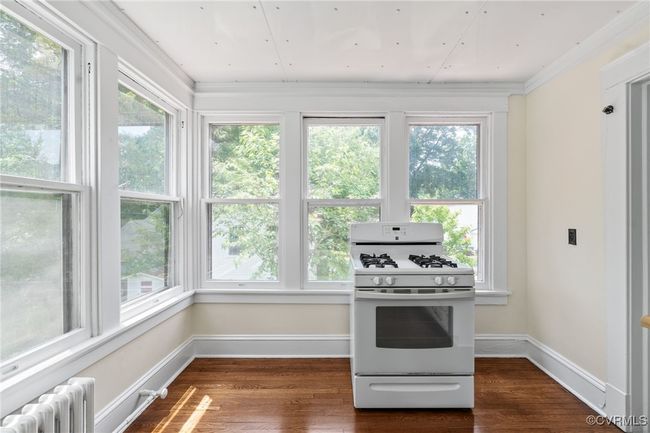 Kitchen featuring radiator heating unit, white range, wood finished floors, ornamental molding, and baseboards | Image 39