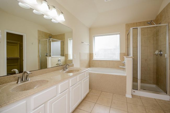 The master bathroomshowcases a standup shower, garden tub, and double sinks. | Image 18