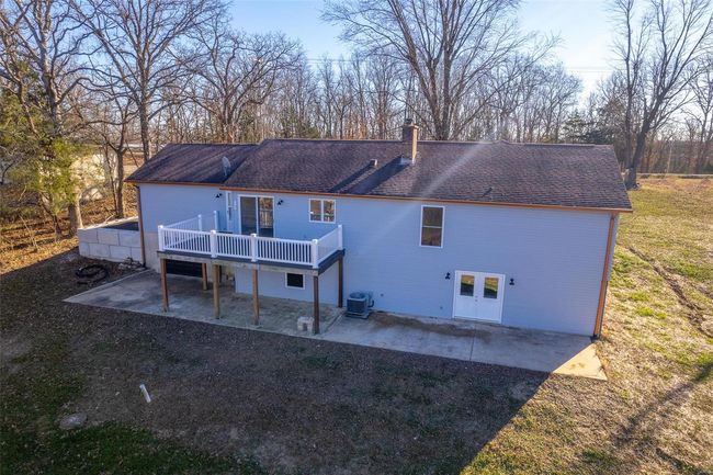 Rear view of property featuring a patio, central AC unit, a lawn, and a wooden deck | Image 9