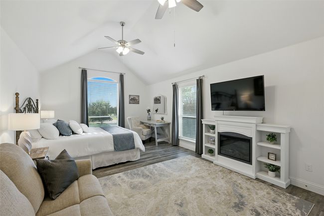 Large second primary upstairs ensuite bedroom with wood-like finished floors, multiple windows, lofted ceiling, ceiling fan | Image 20