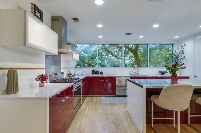 Kitchen with a breakfast bar, light hardwood / wood-style flooring, plenty of natural light, stainless steel stove, and range hood | Image 12