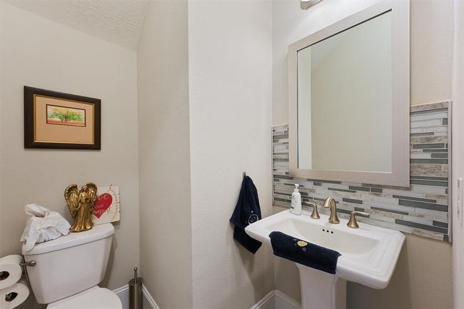Stylish powder room featuring a classic pedestal sink, designer tile backsplash, framed mirror, and brushed nickel fixtures. A perfect blend of function and elegance for guests. | Image 15