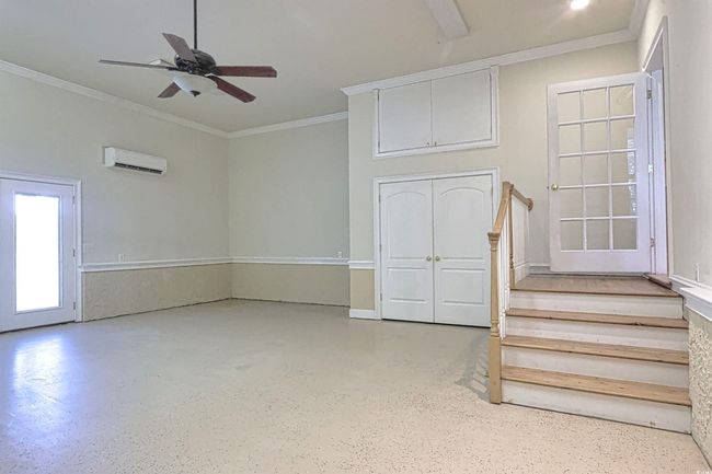 Unfurnished living room featuring a wall mounted AC, ceiling fan, stairway, and crown molding | Image 19