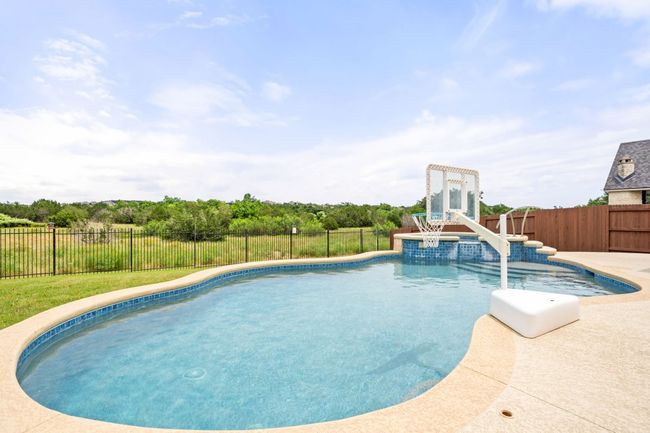 View of swimming pool with a fenced backyard and a patio area | Image 25