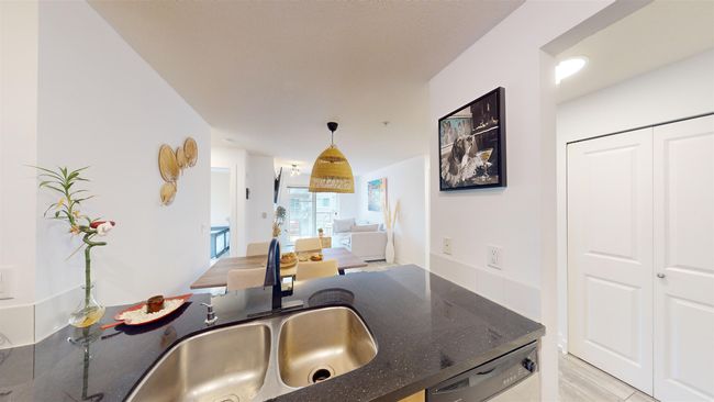 Kitchen with stainless steel dishwasher, a sink, dark stone countertops, and hanging light fixtures | Image 14