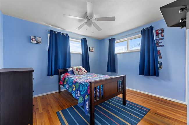Bedroom Two has been freshly painted, featuring lovely hardwood floors and a ceiling fan. | Image 13