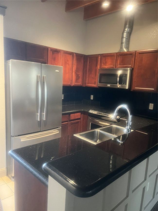 Kitchen with stainless steel fridge, refrigerator, sink, light tile patterned floors, and range | Image 4
