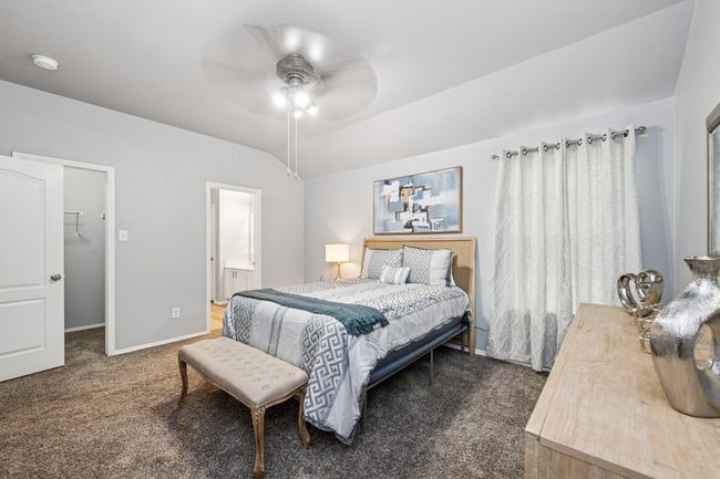 Bedroom featuring baseboards, dark colored carpet, ceiling fan, a walk in closet, and vaulted ceiling | Image 39