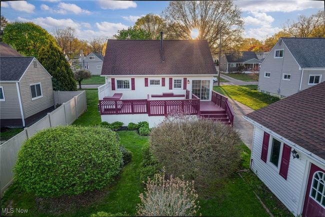 Back of house featuring a residential view, a deck, roof with shingles, a lawn, and fence | Image 42