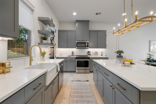 Kitchen featuring light wood-style flooring, stainless steel appliances, light countertops, gray cabinets, and open shelves | Image 11