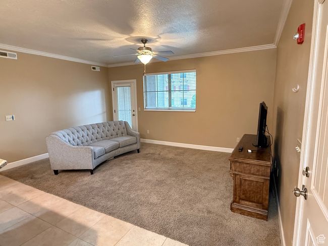 Sitting room with carpet flooring, a ceiling fan, baseboards, ornamental molding, and tile patterned floors | Image 9